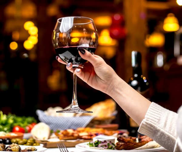 side view a woman drinks a glass of red wine